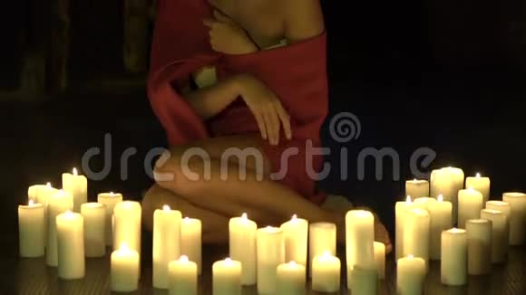聪明的独身女孩坐在地板上靠近燃烧的蜡烛慢慢地视频的预览图