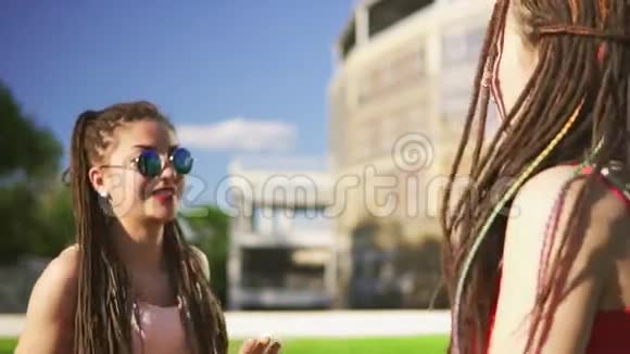 快乐的女人与恐惧坐在草地上夏季公园年轻的朋友在户外聊天跳舞玩得开心视频的预览图