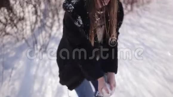 一个美丽可爱的女孩留着深色长发戴着眼镜走在冬天的公园里她微笑着玩雪很开心视频的预览图