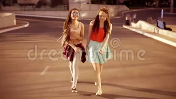 两个快乐的女人带着恐惧走在空荡荡的路上在夏天说话两个时髦的女孩笑着拥抱每一个视频的预览图