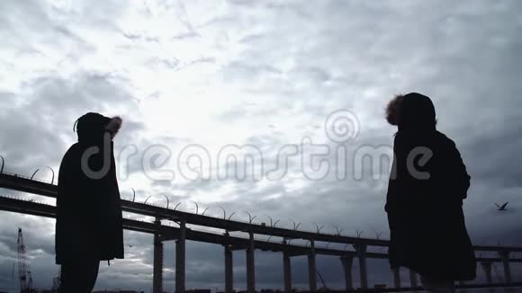 两个人的身影站在海边有一座公路桥视频的预览图