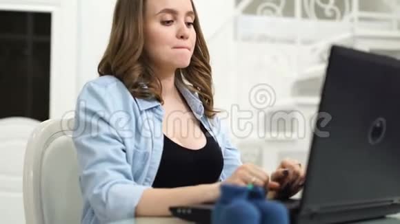 为宝宝网购一位坐在笔记本电脑旁的孕妇为自己的未来在网上商店挑选衣服视频的预览图