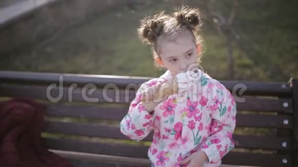 可爱的蹒跚学步的女孩在城市公园吃冰淇淋视频的预览图