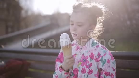 可爱的蹒跚学步的女孩在城市公园吃冰淇淋视频的预览图