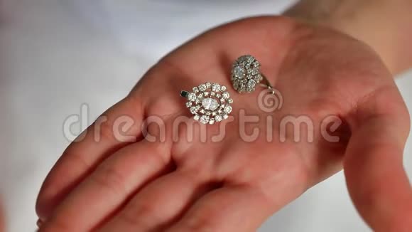 女新娘手里拿着耳环接近美丽的女人戴着闪亮的钻石耳环的生活方式视频的预览图