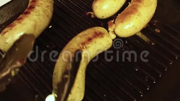 在烤架上准备香肠火钳把油炸的德国疣子放在黑色的鳕鱼上慢点视频的预览图