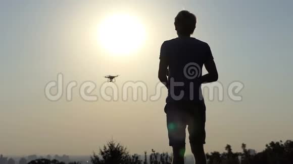 年轻人在太阳落山时用面板操作他的现代无人机视频的预览图