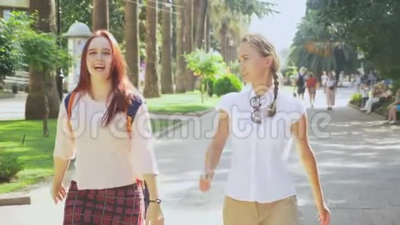 两个女朋友年轻漂亮的女孩在公园里散步女孩们沿着度假小镇散步稳定射击4k视频的预览图