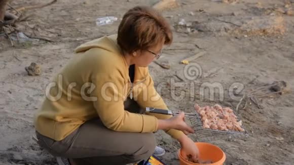 戴眼镜的女人把肉放在烤架上烧烤视频的预览图