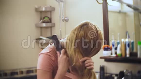 女人掉头发一个金发的女人在镜子前的浴室里梳着长发头发留在上面视频的预览图