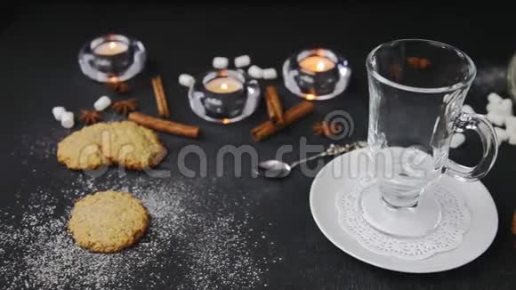 把热巧克力和棉花糖倒入玻璃杯的电影美丽的背景与蜡烛伊利丘姆自制饼干视频的预览图