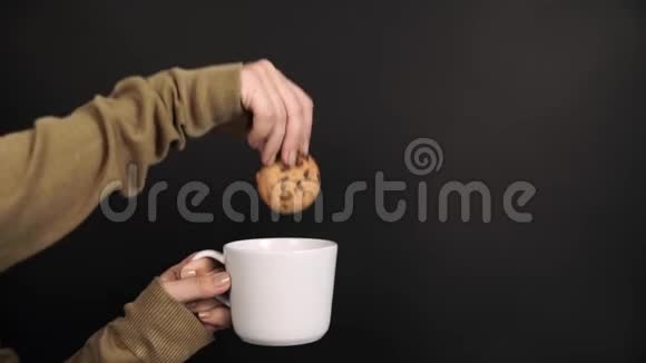 女孩在黑色背景的牛奶杯中灌篮饼干视频的预览图