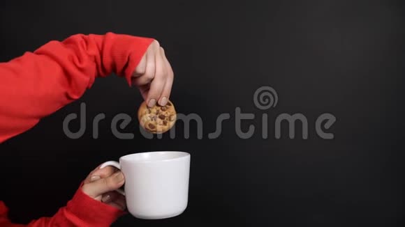 女孩在黑色背景的牛奶杯中灌篮饼干视频的预览图