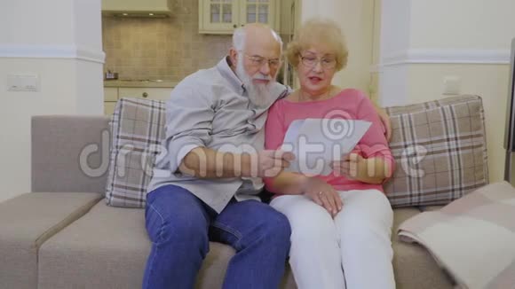 坐在沙发上的老妇人和老人检查他们的房租账单视频的预览图
