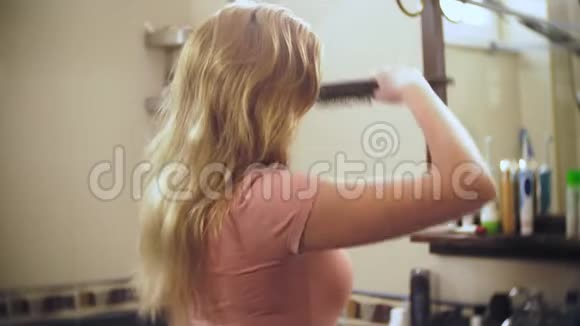女人掉头发一个金发的女人在镜子前的浴室里梳着长发头发留在上面视频的预览图