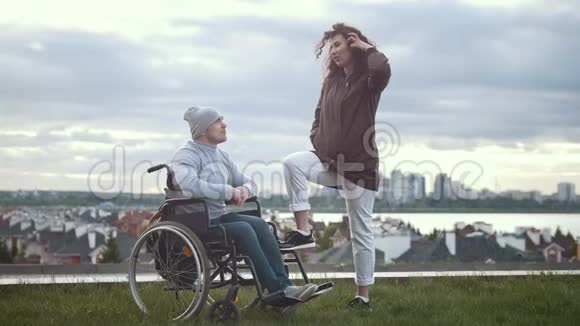 坐轮椅的快乐残疾男子与户外年轻女子拥抱视频的预览图
