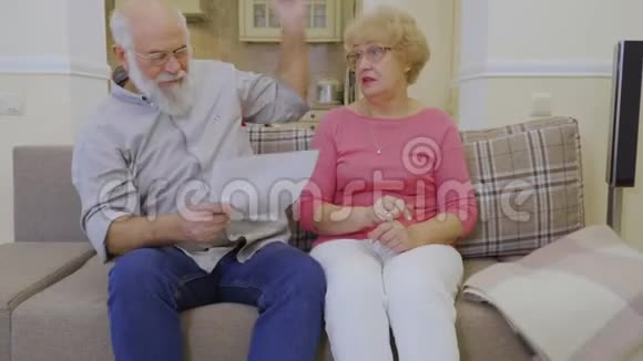 老两口在家里坐在沙发上讨论房租问题视频的预览图