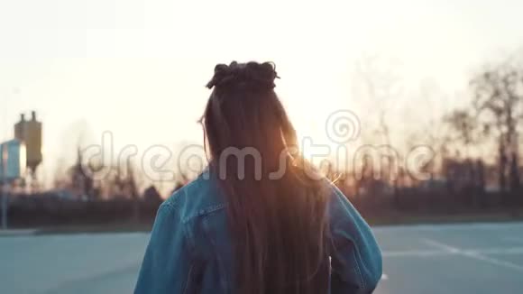 有魅力的年轻女子留着很长的头发穿着牛仔裤朝明亮的阳光跑去转向相机分享一个视频的预览图