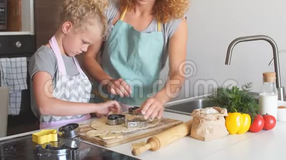 女人和可爱的女儿在厨房做饭为生日聚会做面团视频的预览图