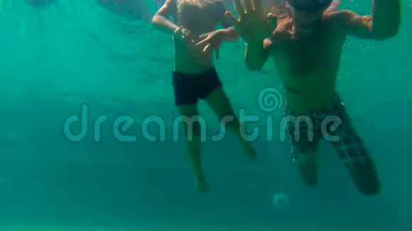 一位父亲教他儿子如何在游泳池里游泳他在水下拍摄了一幅超HD慢动作幼儿男孩和他父亲潜水视频的预览图