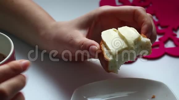 这个女孩吃早餐三明治里面有黄油和可可白色背景的特写视频的预览图