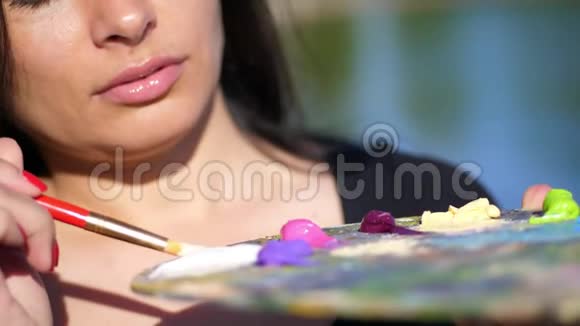 夏天户外在调色板上用颜料特写这位女艺术家在调色板上用画笔混合颜料视频的预览图