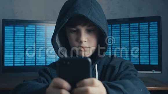 年轻的戴头罩的男孩使用智能手机设备天才少年惊奇黑客系统在网络空间的肖像视频的预览图