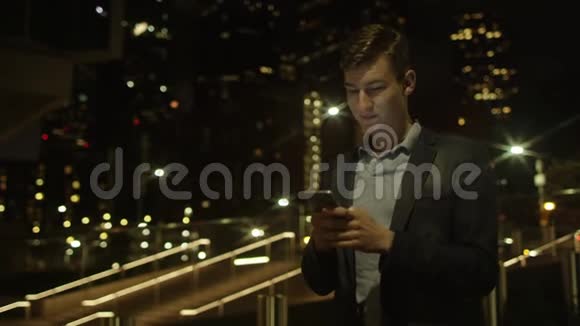 英俊的年轻商人站在街上用智能手机交流视频的预览图