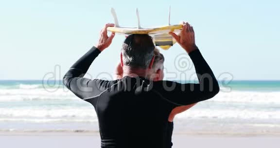 一对年长夫妇带着冲浪板朝大海走去视频的预览图