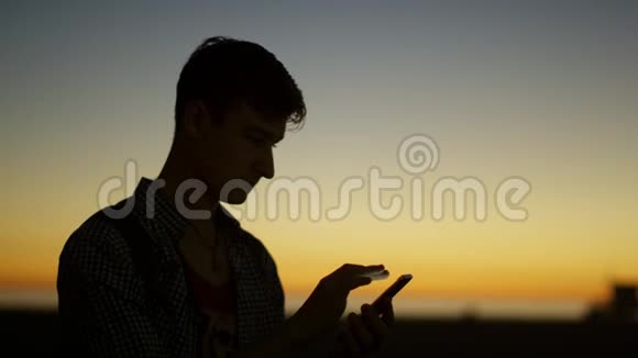 年轻有魅力的男人在黄昏时用智能手机发短信视频的预览图