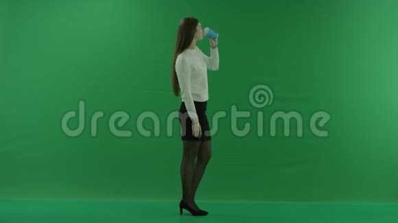 女孩站在她的右边从绿色屏幕上的玻璃杯里喝东西视频的预览图