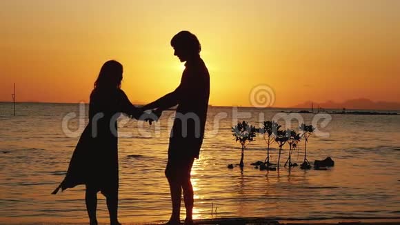 迷人的男人和女人在日落时在海边旋转恋爱中的情侣在度假时一起玩视频的预览图