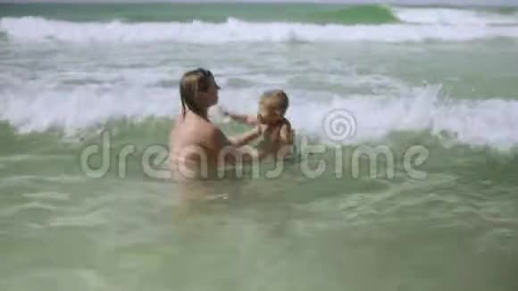 快乐的年轻妈妈和她的小儿子一起在海洋里玩视频的预览图