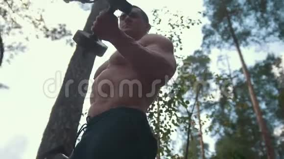 肌肉发达的年轻人在森林里用重铁做哑铃视频的预览图