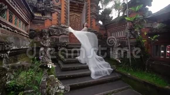 美丽的新娘在巴厘岛的佛寺附近摆姿势在附近散步浪漫的婚礼视频的预览图