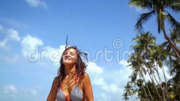 在阳光明媚的夏日里身着比基尼的年轻美丽的黑发女子在异国海滩上奔跑景色宜人视频的预览图