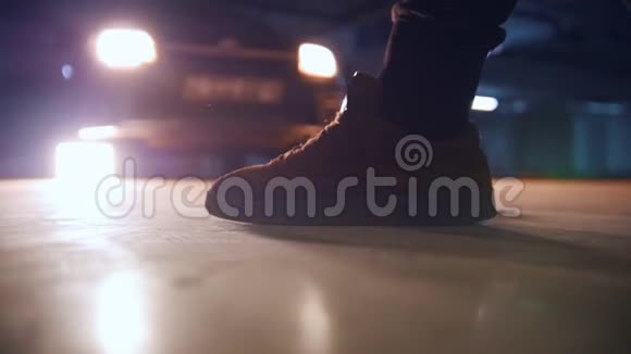 一个男人把鞋带系在汽车前的地下停车场的运动鞋上视频的预览图
