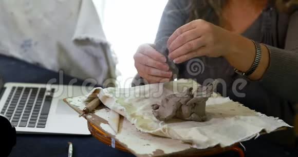 成熟的女性陶工在使用笔记本电脑4k的同时塑造粘土视频的预览图