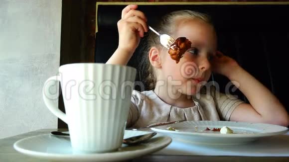餐桌上的女孩喝茶吃盘子里的蛋糕视频的预览图