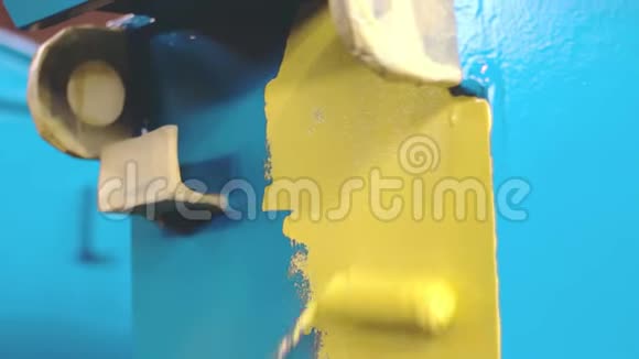 人正在用手辊把蓝色的金属细节画成黄色工厂的油漆工视频的预览图