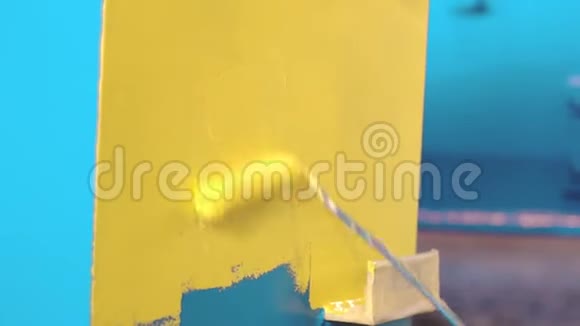 人正在用手辊把蓝色的金属细节画成黄色工厂的油漆工视频的预览图