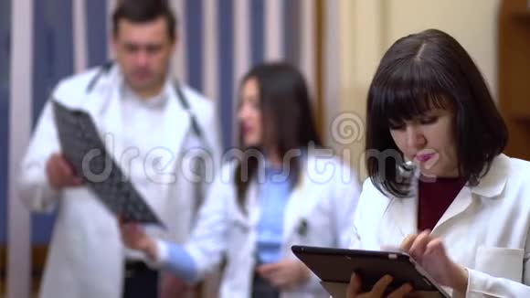 一位女医生手里拿着一块药片在背景中医生检查x光视频的预览图