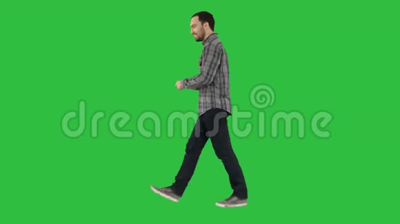 年轻的智能休闲男子在手机上行走和阅读信息的绿色屏幕色度键视频的预览图