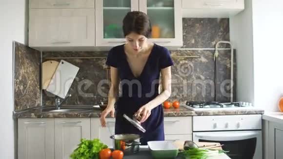 年轻微笑的女人在家厨房做饭的时候用鸡翅打开锅视频的预览图