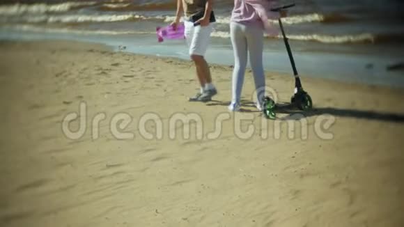 年轻人拿着滑板车在海滩上散步视频的预览图