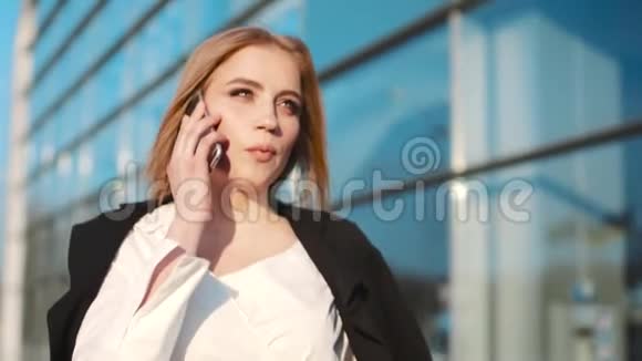 华丽时尚的年轻女子穿着优雅的服装穿过机场航站楼在电话中交谈天气晴朗视频的预览图