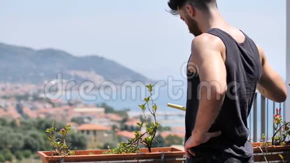 青年男子在公寓阳台上浇灌植物视频的预览图