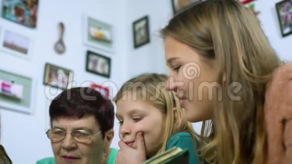 祖母和四个孙女在家看旧相册的特写视频的预览图