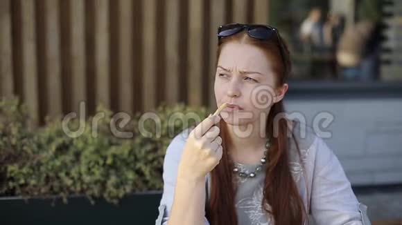 白种人中年妇女下班后坐在夏天的咖啡馆里吃薯条视频的预览图