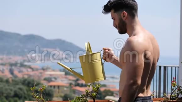 青年男子在公寓阳台上浇灌植物视频的预览图
